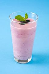 Blueberry smoothie in a glass on a blue background
