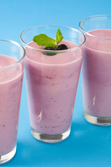 Blueberry smoothie in a glass on a blue background
