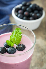 Blueberry smoothie in a glass on a rustic table
