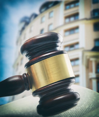 Gavel and book on wooden table on building background. Auction concept