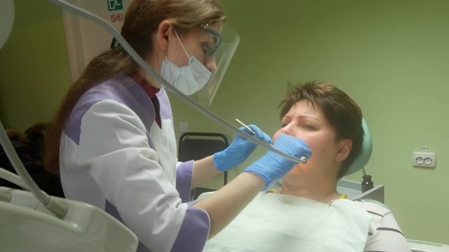4k Dentist making professional teeth cleaning female patient at the dental office