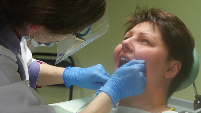 4k Female patient with open mouth receives an injection at the dentist