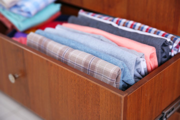 Neatly folded clothes in wooden drawer