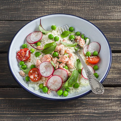 Fresh salad with cous cous, vegetables and baked salmon. Healthy tasty food. On a dark wooden background