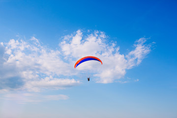 Paraglider flying against a backdrop of mountains and sea