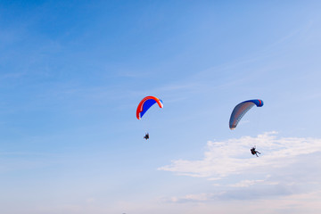 Paraglider flying against a backdrop of mountains and sea