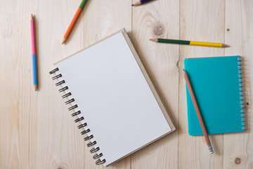 Blank page of notebook and colorful pencils for drawing on the wooden table. top view