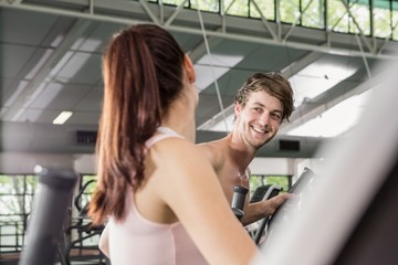 Happy woman and man exercising on the elliptical machine