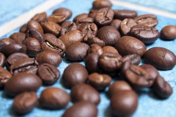 Roasted coffee beans on blue ceramic tiles.