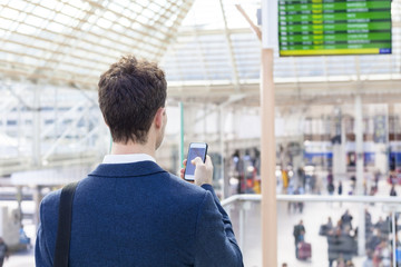 Traveler sending text message on smartphone  in train station