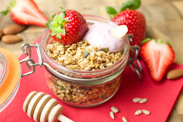 

Homemade granola in a glass jar and fresh strawberries 