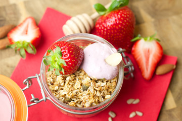 

Homemade granola in a glass jar and fresh strawberries 