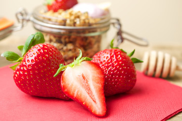 

Homemade granola in a glass jar and fresh strawberries 