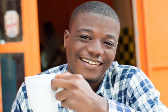 Happy young man holding a cup of coffee in hand.