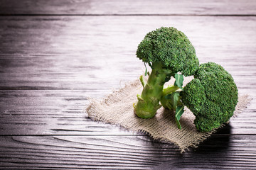Bunch of fresh green broccoli on brown plate over wooden background
