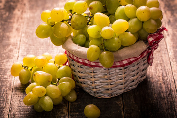 Bunch of grapes and in basket on wooden table.