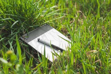 graphics tablet with a pen lying in the thick grass of spring