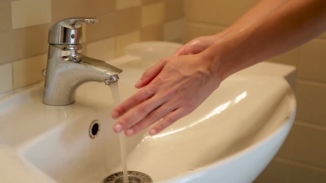 girl washes her hands under the tap