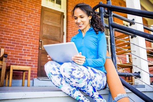 Woman using digital tablet while sitting on porch