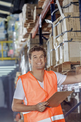 Obraz premium young smiling warehouse worker running inventory check