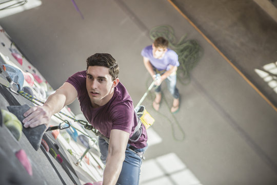 High angle view of athlete climbing rock wall in gym