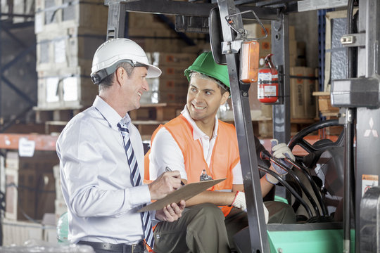 Floor Supervisor Consulting With Forklift Operator