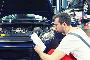 Kundendienst in der Autowerkstatt - Mechaniker checkt Fahrzeug // car repair shop inside