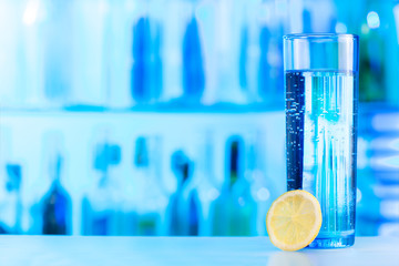 One glass of mineral water with lemon slice at bar