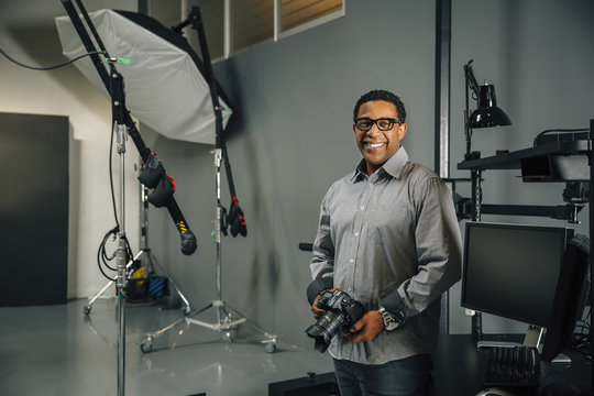 Mixed race photographer holding camera in studio