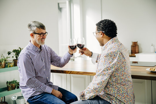Gay couple toasting with wine at counter