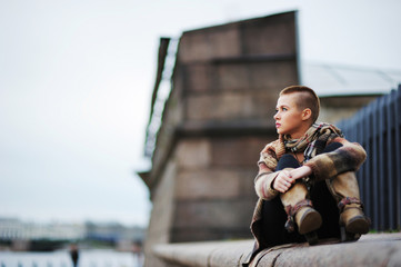 a beautiful short-haired girl sitting on the parapet with his legs in boots