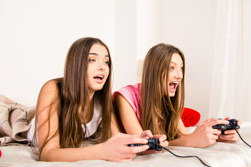 Emotional pretty girl lying in bed and plaing video games © deagreez
