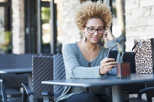 Black Woman Using Cell Phone At Cafe