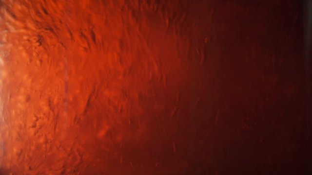 Adding orange Liquid into Transparent Fluid and creating bubbles.