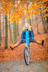 Obraz premium Happy active woman riding bike in autumn park.