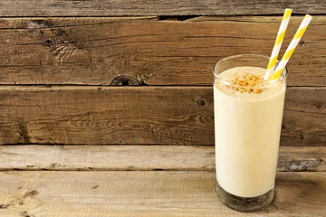 Foto auf Acrylglas Milchshake Erdnussbutter-Bananen-Hafer-Frühstücks-Smoothie mit Papierstrohhalmen vor rustikalem Holzhintergrund