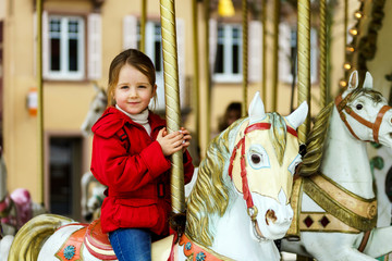 Little girl sitting on carousel horse