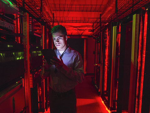 Technician using digital tablet in server room