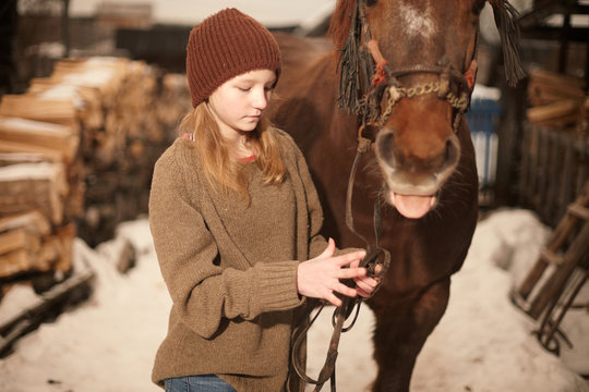 Teenage girl with a horse in snowy field