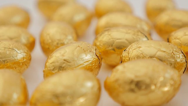 Chocolate Easter eggs wrapped in golden foil grouped on whit surface 4K 2160p 30fps UltraHD footage - Golden chocolate egs wrapped in luxory gold foil 4K 3840X2160 UHD video