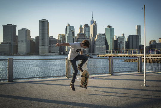 Caucasian skateboarder doing trick at waterfront, New York, United States