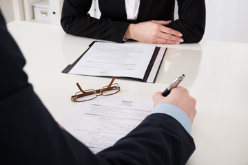 Businessperson Holding Pen Over Resume
