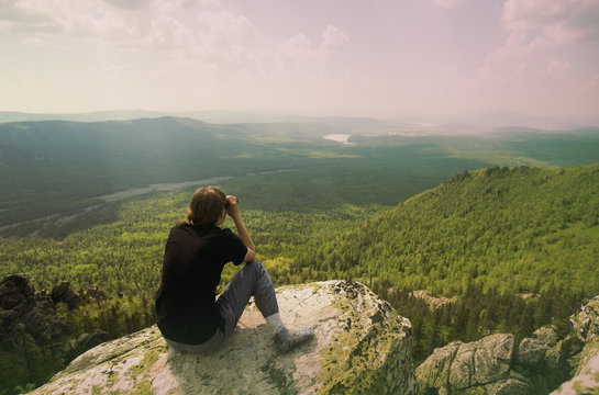 Caucasian hiker admiring remote landscape from rocky hilltop