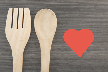 heart with wooden spoon and fork on wooden background: health concept