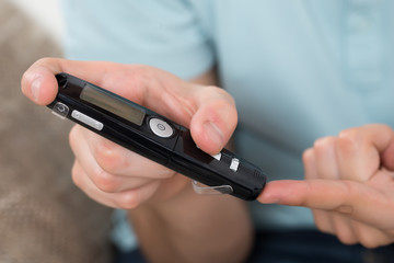 Person Measuring Blood Sugar With Glucometer