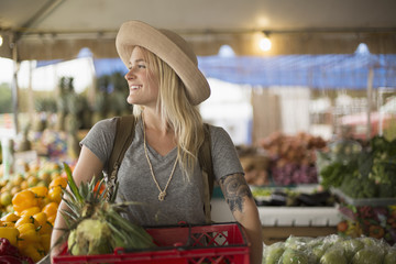 Smiling woman carrying crate of fruit in farmer's market