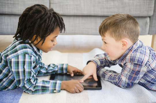 Boys playing with digital tablet on sofa