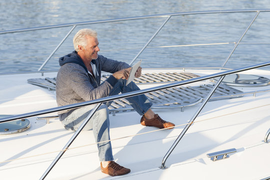 Caucasian man using digital tablet on sailboat deck