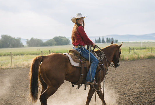 Caucasian cowgirl riding horse on ranch