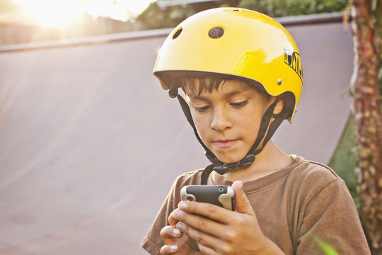 Mixed race boy in helmet using cell phone